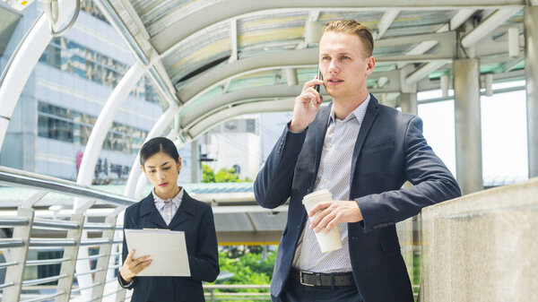 деловые люди леди и кавказский мужчина говорить со смартфоном и ходить по пешеходной дорожке
