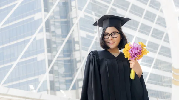 Студентка в выпускном классе с цветочным букетом — стоковое фото