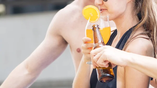 Woman with sunglasses in swimming wear holds glass of cocktail orange juice — Stock Photo, Image