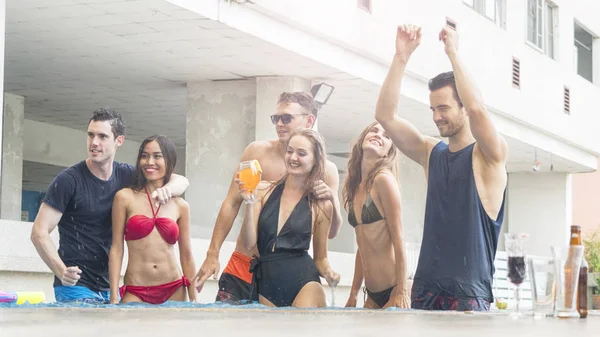 Amigos teniendo fiesta y bailando en una piscina - Moda de verano playa bikini delgado músculo mujeres y hombres personas disfrutando de vacaciones en un hotel de resort tropical con bebida de botella de cerveza — Foto de Stock