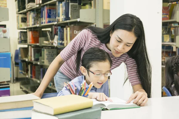 woman teacher and kid student learn with book at bookshelf background