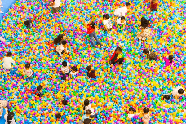 top aerial view of plastic balls pool with family childs and kids playing in the pool. Concept top view background colorful pixel.