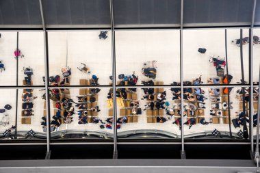 Havaalanında seyahat etmek için bavul ve evrak çantasıyla kuyrukta bekleyenlerin yansıma camı.