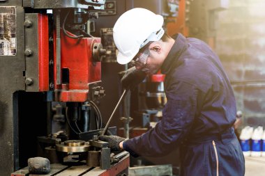 Profesyonel Asyalı işçi, Depo fabrikasındaki büyük makineyi tamir ediyor. Konsept Mühendisi Fabrikada güvenlik ile birlikte çalışır ve kontrol eder.