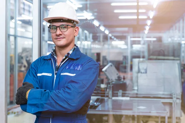 Portrait of manual man worker is standing with confident with blue working suite dress and safety helmet in front the glass wall of high technology clean industry factory.Concept of smart industry worker operating.