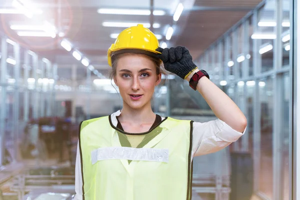 手工女工的形象正自信地站在高科技洁净工业工厂的玻璃墙前 带着蓝色工作服 绿色反光的安全衣和安全帽 智能工业工人的概念 — 图库照片