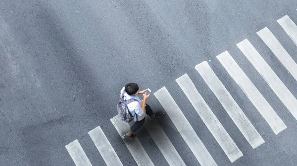 Human life in Social distance. Aerial top view with blur man with smartphone walking at pedestrian crosswalk on grey pavement street road with empty space.