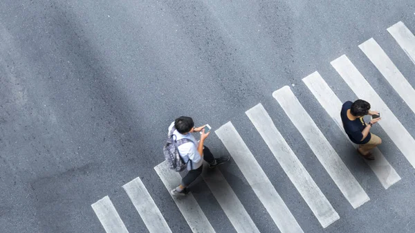 Sosyal mesafede insan hayatı. Akıllı telefonlu bulanık bir adamla hava üstü görüntüsü. Boş alan olan gri kaldırım caddesindeki yaya geçidinde diğer insanlarla sohbet ediyor..