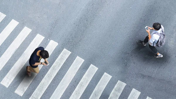社会的距離における人間の生活 空中からの眺めスマートフォンを持つぼやけた男空の空間を持つ灰色の舗装道路を横断歩道で他の人の会話を歩く — ストック写真
