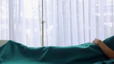 Asyalı kadın doktor, yaşlı yaşlı bir hastaya tavsiye veriyor. Tekerlekli sandalyede, hasta odasında oturuyor. Hastanenin arka plan beyaz perdesi..