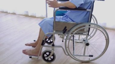 Hastanede tekerlekli sandalyede oturan hasta, yaşlı, Asyalı yaşlı bir adam ve ona tıbbi tedavi öneren kadın doktor..