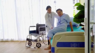 Hasta, yaşlı, Asyalı yaşlı bir adam hastane yatağında dinleniyor. Doktorun tavsiyesi yatağın yanında..