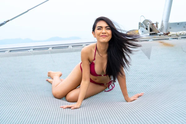 sexy asian woman in bikini lay down relaxing on  cruise yacht with background of blue water sea Concept luxury travel with nature of sea.