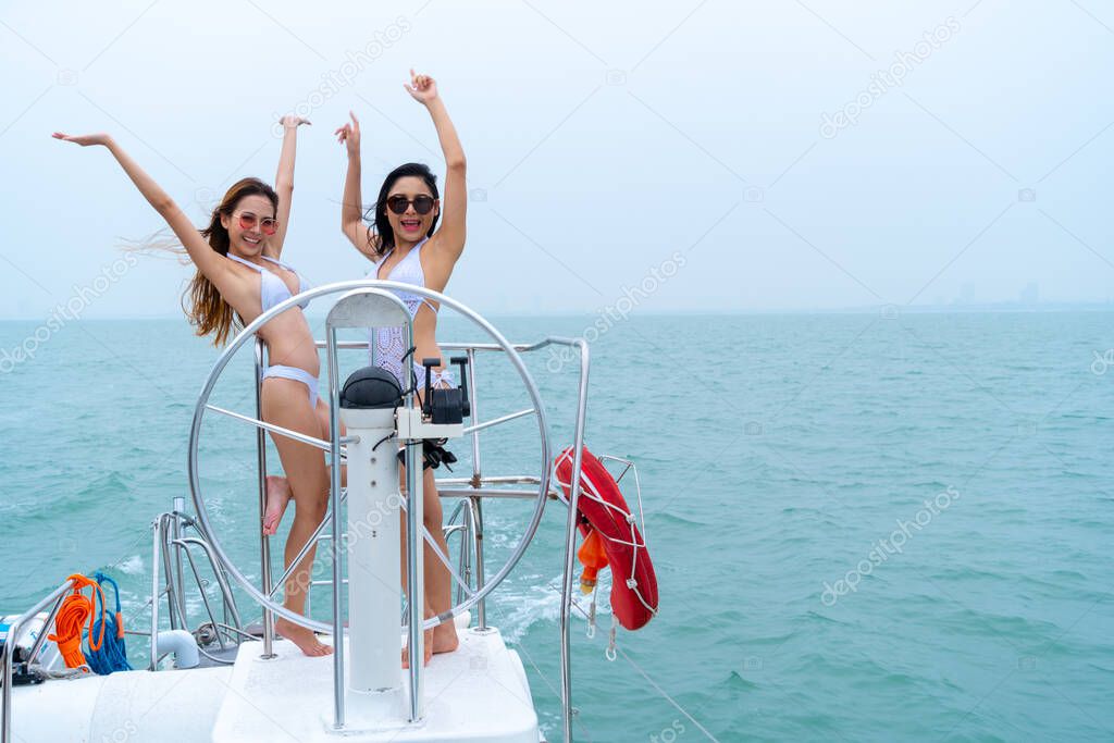 bikini sexy girl stand and dance with driver hand steering wheel on boat yacht with background of sea and sky