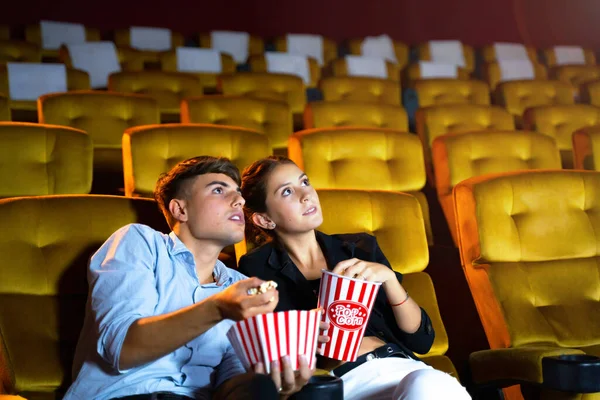 看电影的年轻夫妇在电影院里感到害怕和害怕 手里拿着小吃桶 把爆米花扔在座位上 — 图库照片