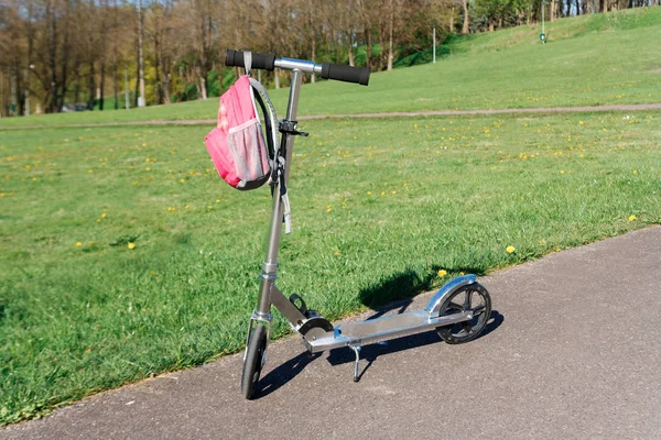 Scooter ve yeşil çayır yanında sırt çantası.