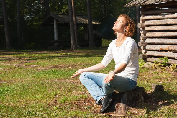 Genç bir kadın doğa üzerinde meditasyon.