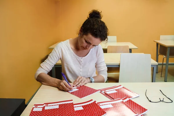 Öğretmen masa başında oturan ve okul not defterleri kontrol