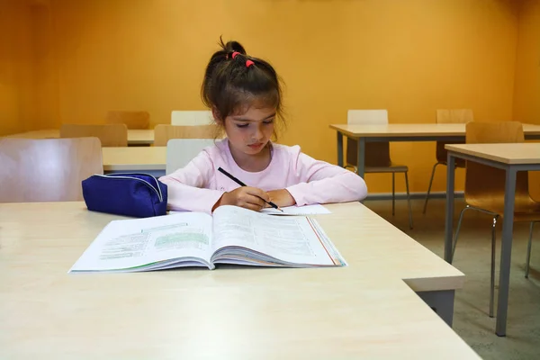 Sınıf ve okumak için ve bir kalemle yazmak için öğrenme bir kızdır, o kalemle onun not defterinde yazıyor