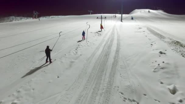 Лыжники и сноубордисты поднимаются на подъемник по склону — стоковое видео