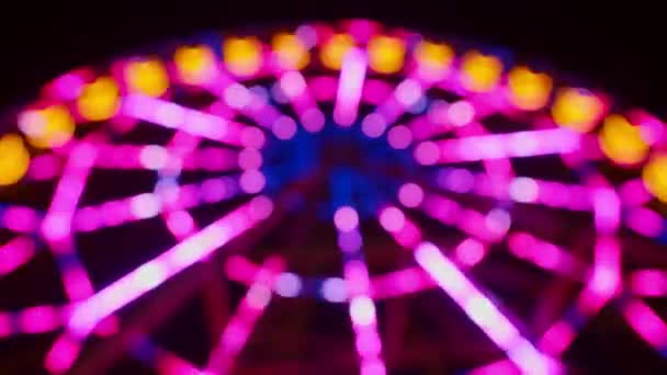 Blurred Ferris wheel with colourful lights at night — Stock Video