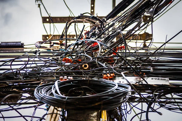 Tangled electrical wires on urban electric pole.