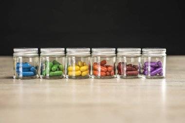 Dizilmiş renkli doğum kontrol hapları ile dolu şişeler