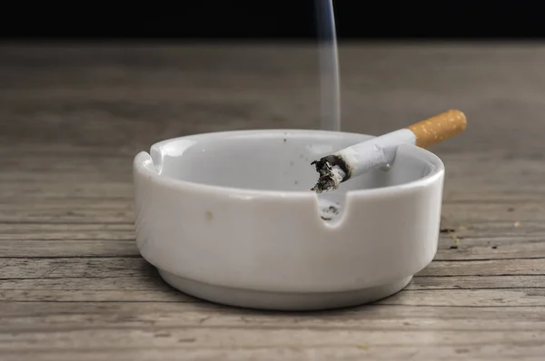 Lit cigarette in ashtray — Stock Photo, Image