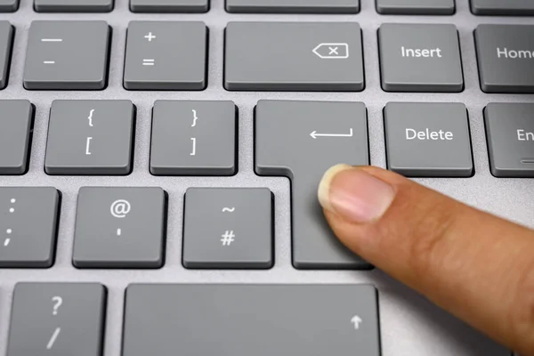 Finger pressing the enter key on keyboard