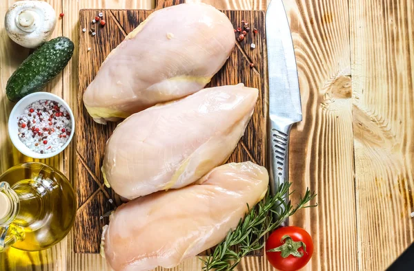 raw chicken fillets on wooden cutting board, top view