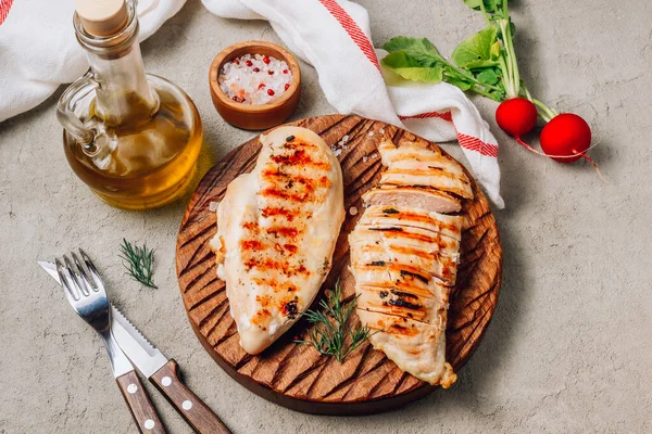 Grilled chicken fillets on rustic wooden cutting board on concrete background. Top view. Healthy food concept