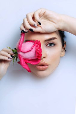 Beauty portrait of pretty young woman takes a bath with milk and roses in hand