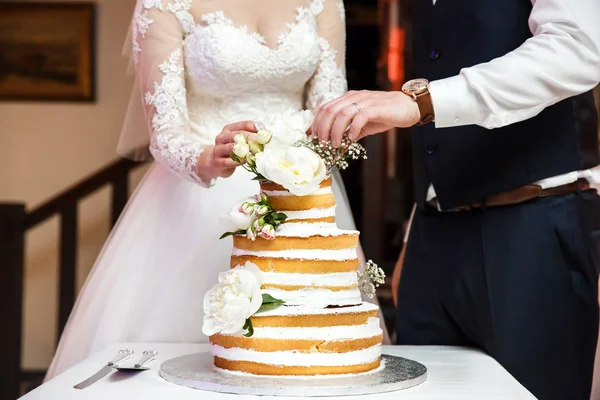 Noiva e noivo na recepção do casamento cortando o bolo de casamento com flores — Fotografia de Stock