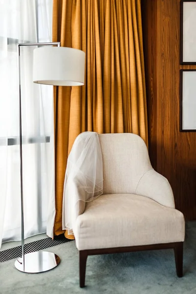 White chair covered with a veil and tall lamp