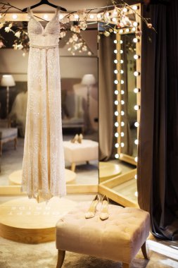 Gelinlik asılı bir askı ve düğün ayakkabıları bir sandalyede ayağa