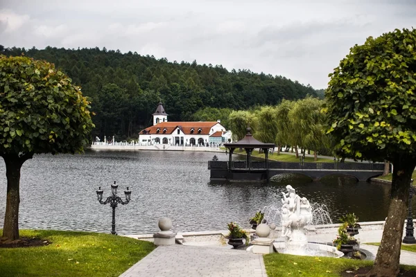 Dom i kamień foutain w lesie nad jeziorem — Zdjęcie stockowe