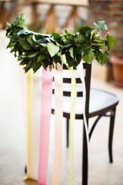 Düğün sandalye yeşil yaprakları ve renkli kurdeleler ile süslüdür
