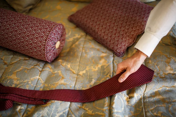 Крупним планом рука нареченого бере краватку з ліжка — стокове фото