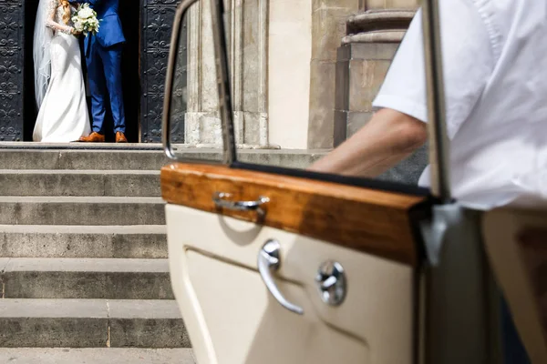 Braut und Bräutigam gehen von der Kirche ins Auto — Stockfoto
