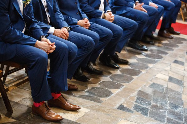 Stylish groomsmen sit during the ceremony in the church