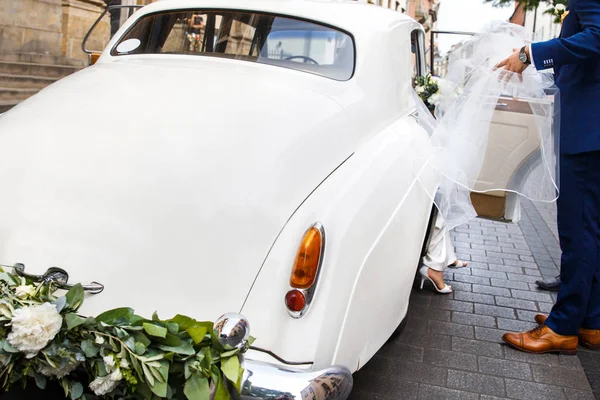 Bräutigam hilft der Braut. Retro weißes Auto — Stockfoto