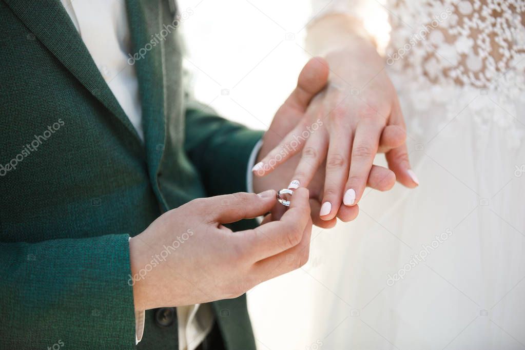 Groom wears ring on bride's finger. Wedding day