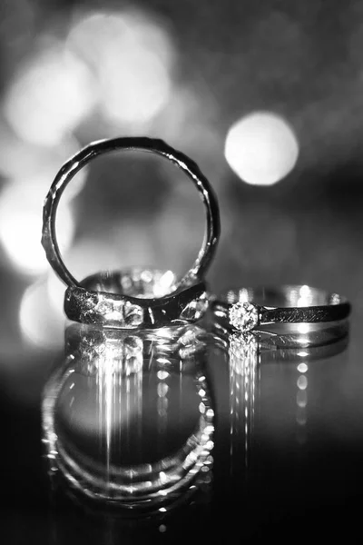 Tres anillos de boda en la superficie reflectante con reflejos —  Fotos de Stock