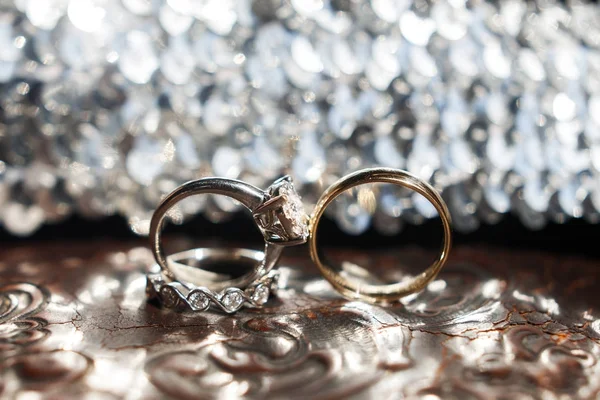 Três alianças de casamento na superfície refletora com destaques — Fotografia de Stock
