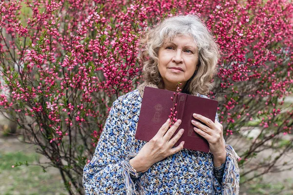 elderly woman holding a book outdoor