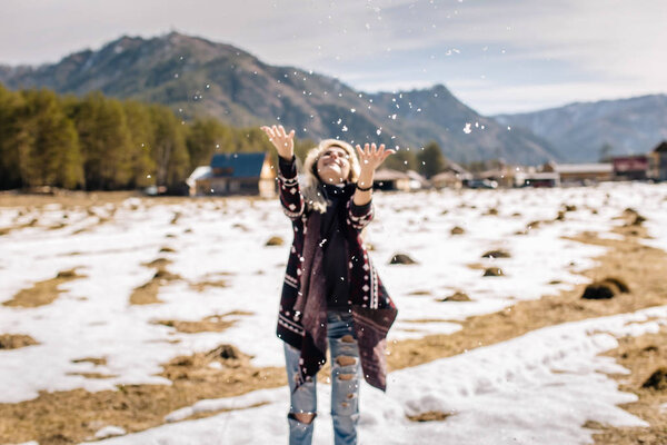 girl in a knitted jumper throws snow