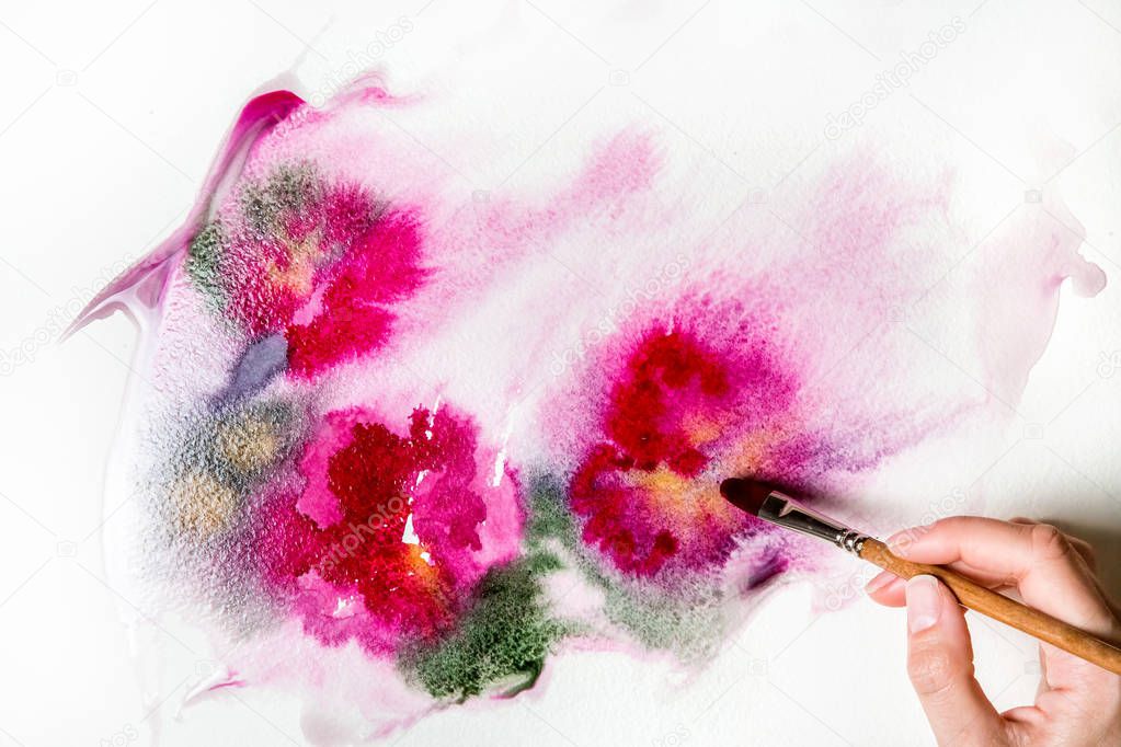 female hand painting pink flowers on white paper