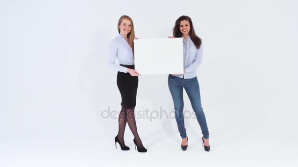 Две улыбающиеся привлекательные девушки ходят и держат плакат — стоковое видео