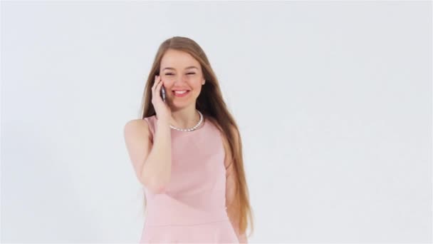 Улыбающаяся привлекательная девушка в розовом платье говорит по телефону — стоковое видео