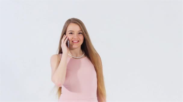 Smiling attractive girl in pink dress talking phone looking at camera — Stock Video